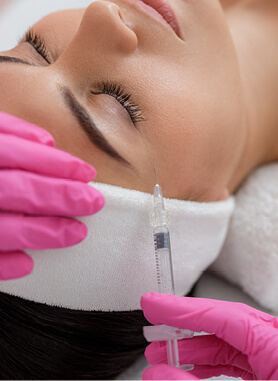 spa personnel inserting needle into woman's forehead